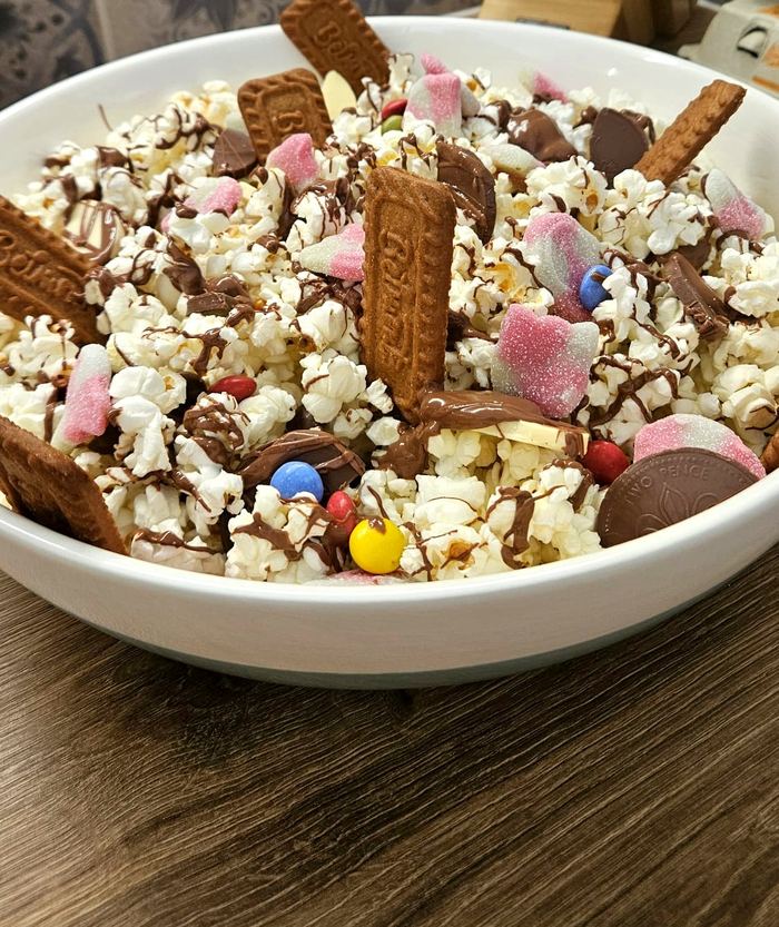 Bowl of loaded popcorn with biscuits, chocolate coins and sweets