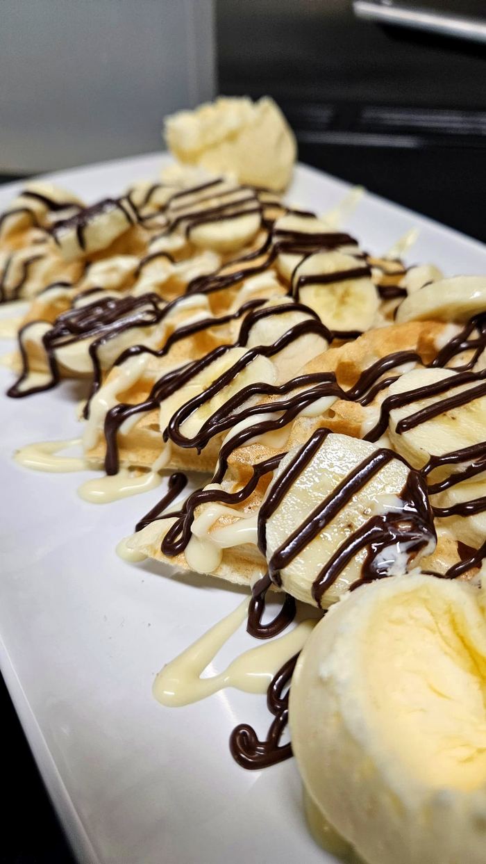 Waffles topped with sliced banana and chocolate drizzle