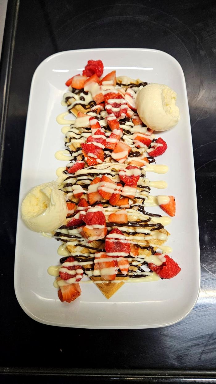 Waffles topped with fresh strawberries, raspberries and chocolate drizzle