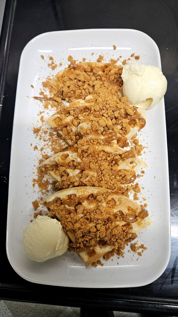 Waffles topped with Biscoff crumb, caramel sauce and vanilla ice cream
